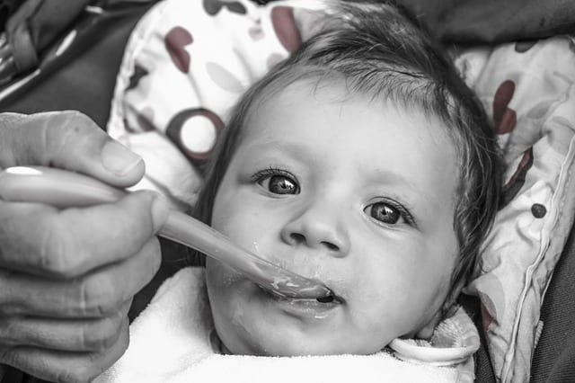 An infant being spoon-fed using the best baby spoons. 