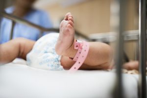 A baby in the crib wears diaper.