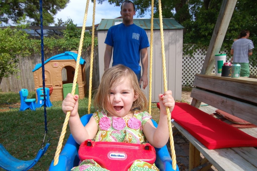 A young girl experiencing sheer joy on a swing, with her safety being of utmost importance.