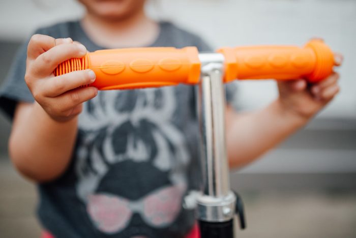 A kid with his favorite scooter & orange scooter