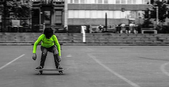 Person in a neon green shirt skateboarding in a grayscale urban setting.