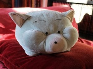 A plush pig on a red cushion.