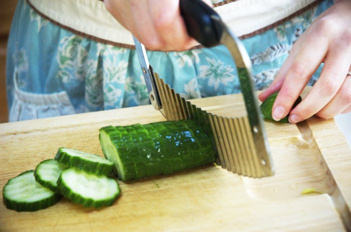 A woman cutting the vegetables on the kitchen countertop