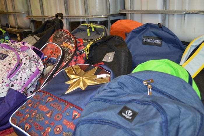 A collection of various colorful backpacks, including a blue Jansport backpack, displayed together, suggesting a setting like a medical school locker room or a student gathering area.