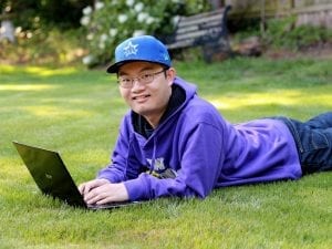 A 13-year-old boy lies comfortably on the ground, engrossed in his laptop. He's immersed in a world of digital exploration, fingers dancing across the keyboard as he engages with the screen. The glow of the laptop illuminates his focused expression, capturing a moment of youthful curiosity and technological connection