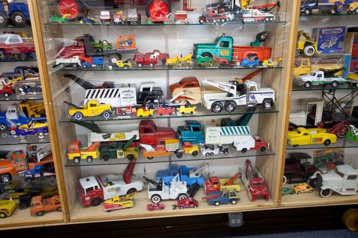 Toy Trucks: Collection of toy tow trucks for kids displayed on shelves, featuring various models and colors.