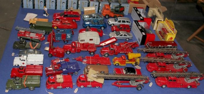 Toy Tow Truck: Collection of assorted vintage toy vehicles, including fire engines and trucks, displayed on a blue cloth.