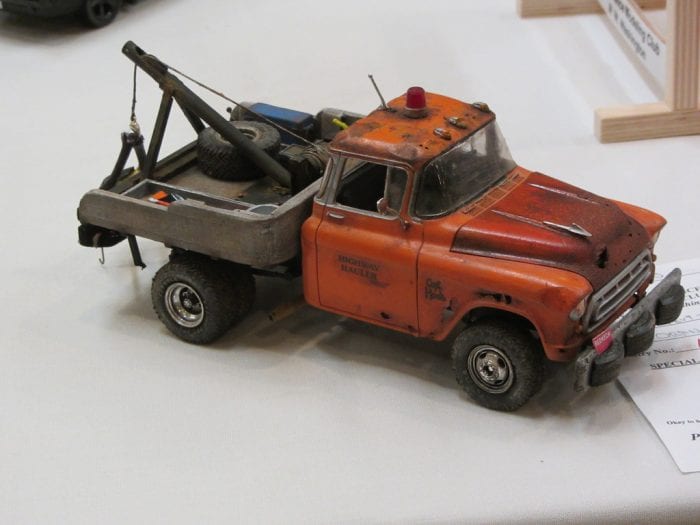 Toy Truck: Rustic orange vintage toy tow truck with a weathered look and realistic details, displayed on a table.