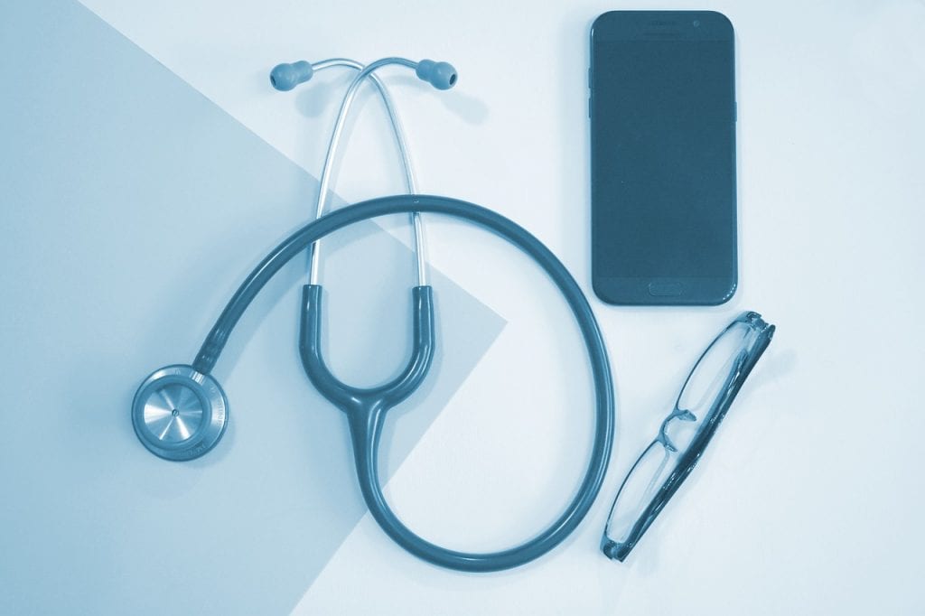 nursing must-have tools when taking nursing program A monochrome image showcasing a stethoscope, smartphone, and eyeglasses, representing essential items for a medical student's daily use.