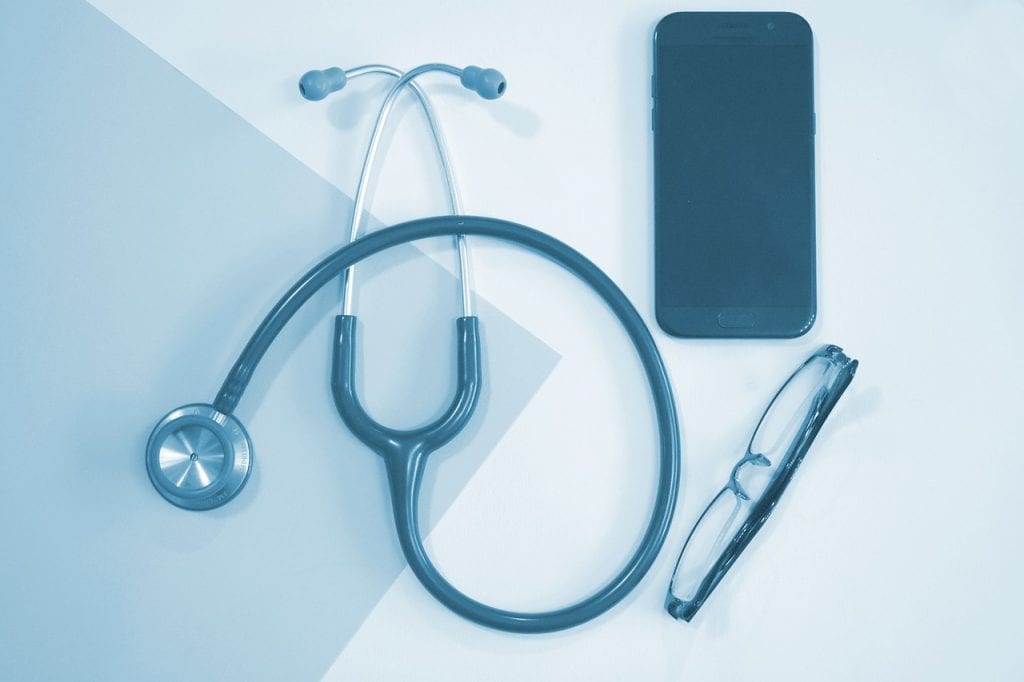 A monochrome image showcasing a stethoscope, smartphone, and eyeglasses, representing essential items for a medical student's daily use.