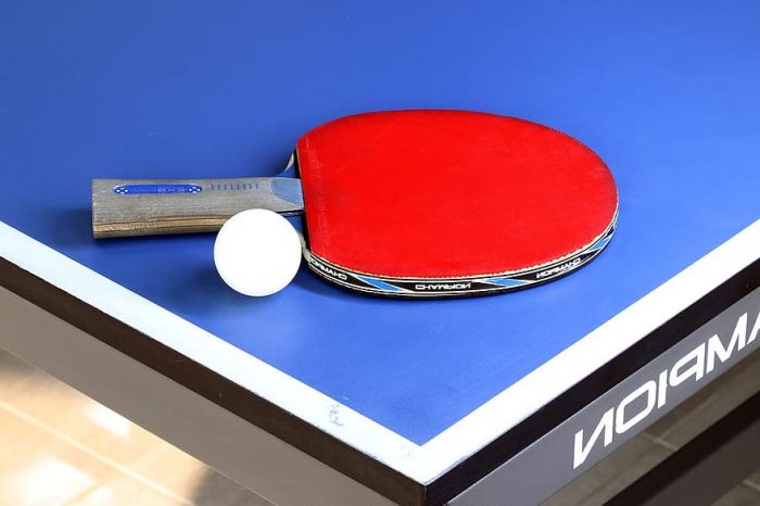 Table tennis racket and ball on top of the table