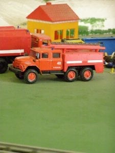 A fire truck toy near a red toy fire station.