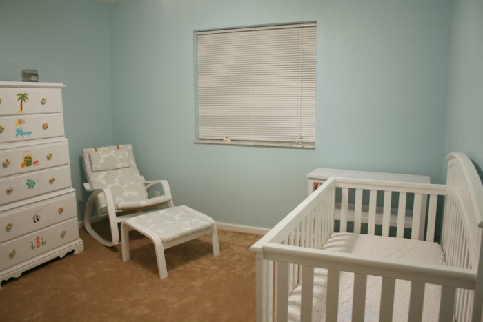 A simple yet cozy baby's dresser. There is a white chair glider, also known as a rocker chair. There is also a small long table where you can change the baby's diaper, Aside from that, there is a tall dresser where you can put all the baby's items like diapers, bottles, dresses, and many more. There is a crib where your baby can sleep peacefully. The whole room has a minimalistic design. 