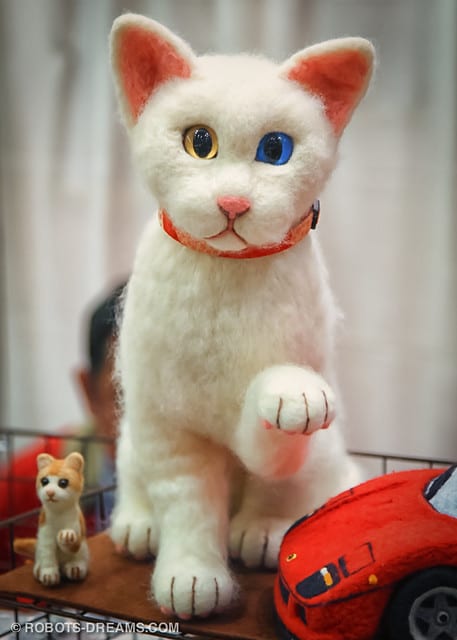 A white robotic cat with yellow eye on the left and blue in the right 