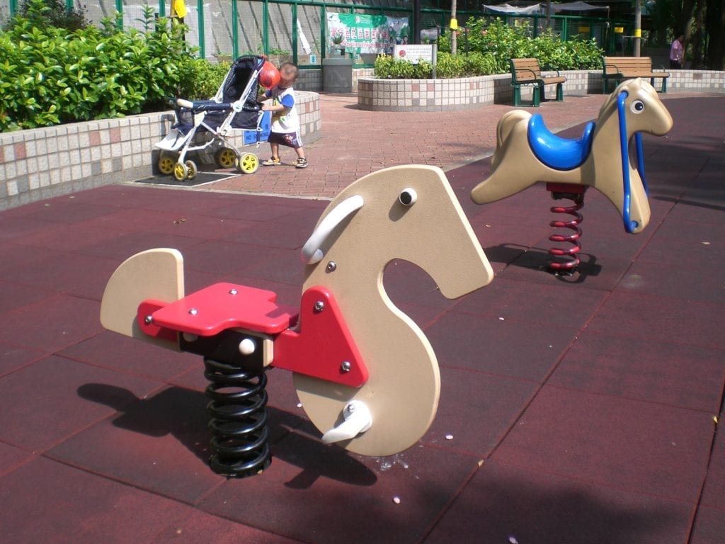 Spring rocking horses in the park with blue and pink colors.