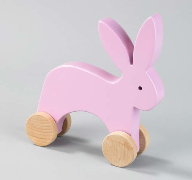 pink wooden baby toy that can be sat on by a little kid