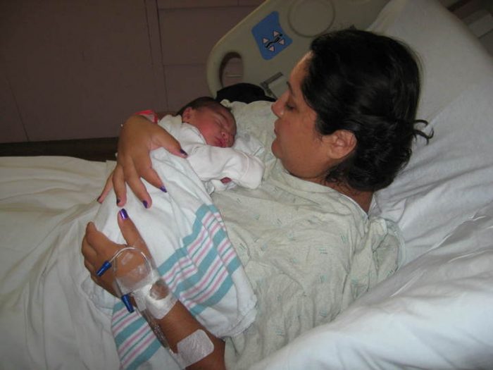Postpartum girdle after giving a birth. She is looking to her gorgeous baby with a heartwarming smile to her face.
