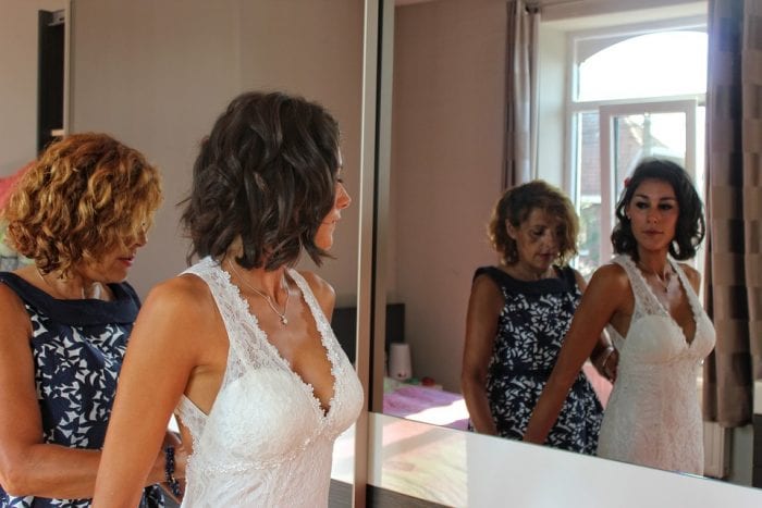 A mother helping her daughter during her gown fitting in preparation for her wedding