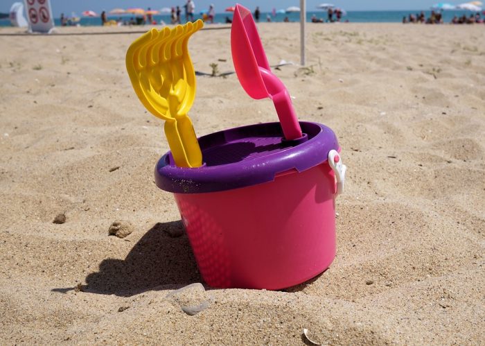A pink pail for children to play in the beach sand.