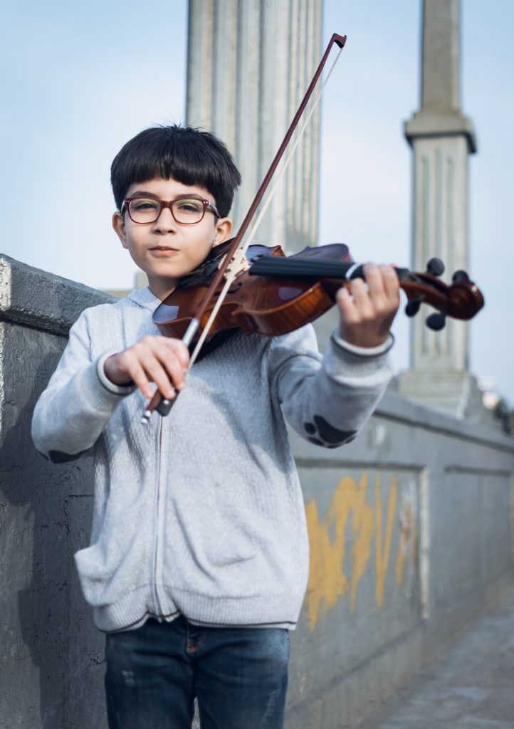 A cute boy playing a real violin. You may want to start with a toy violin before letting your child get on with a real violin.