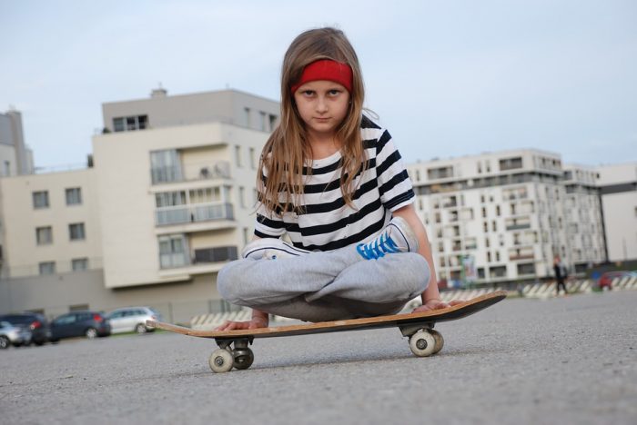 A kid riding a skateboard. A skateboard can teach proper coordination. 