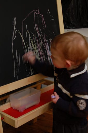 Young child joyfully engaged with a top-rated chalkboard, fostering his creative expression while developing essential artistic abilities and cognitive growth.
