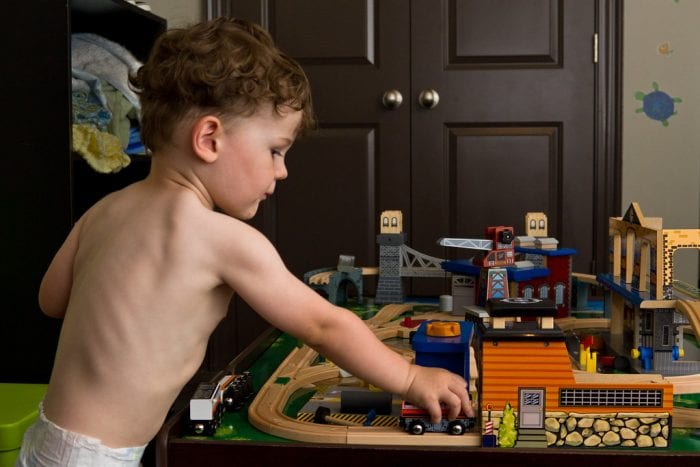 A kid plays with his Imaginarium Metro Line Train Table attentively inside the living room. 