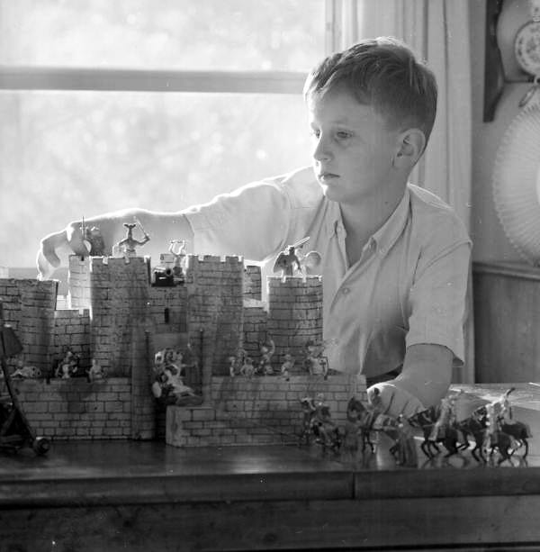 A kid is playing with his castle toy. The picture is in black and white.