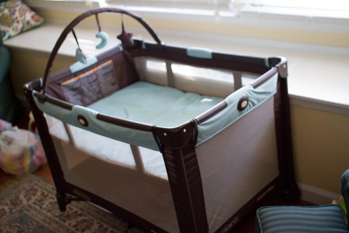 A brown pack n play portable crib with a baby mattress. This pack n play is ideal for any gender.