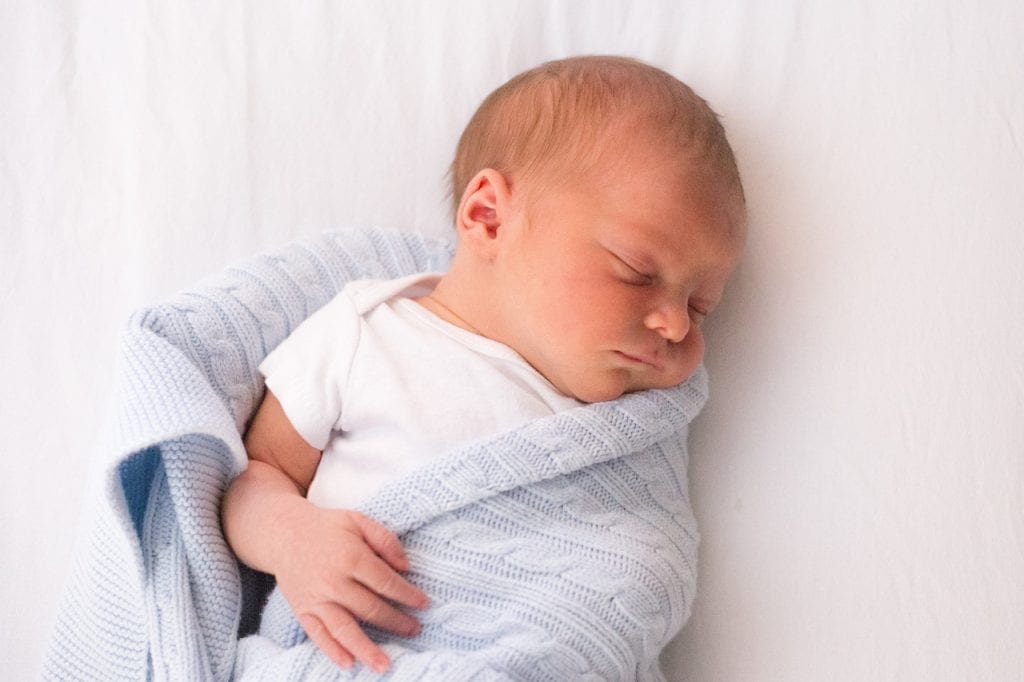 A baby sleeping soundly in his room with a sock