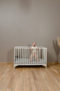 One of the best white baby cribs that promotes peace. The baby inside the crib is standing