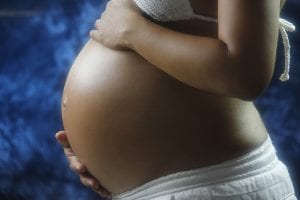 Pregnant woman cradling her belly, suggesting inquiry into whether babies fart in the womb.