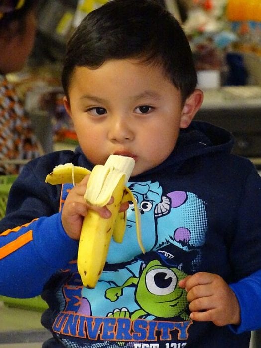 A kid eating his banana. It is amazing that there are some children that they like bananas, apples, and other healthy food.