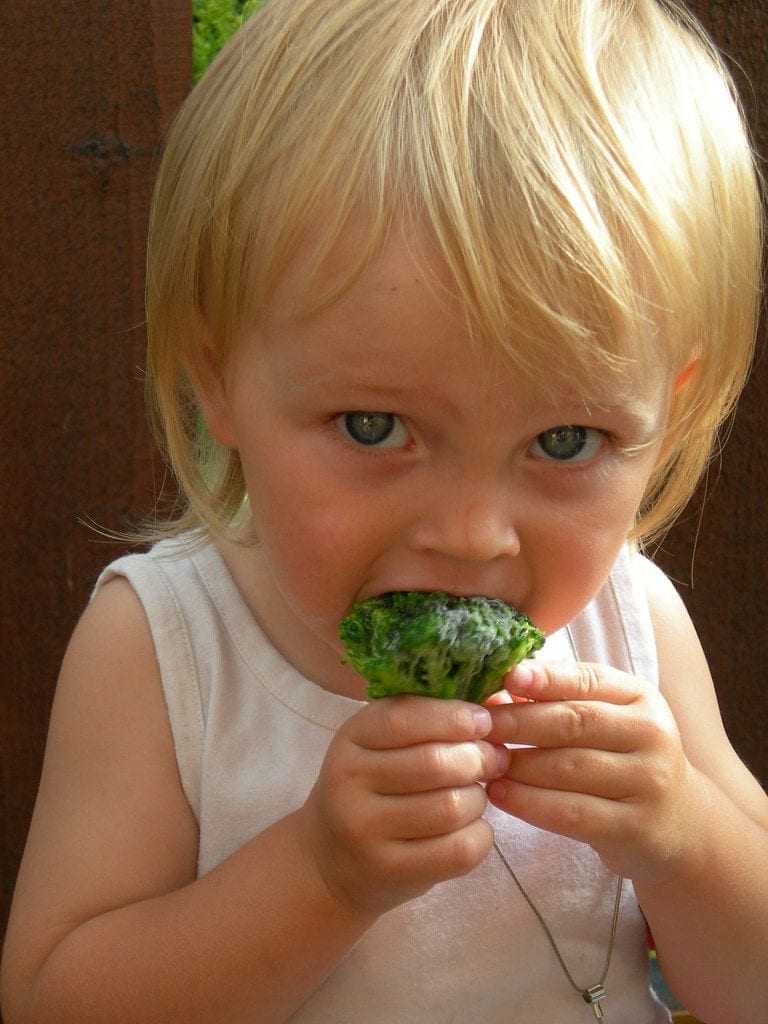 A toddler consuming her vegetables