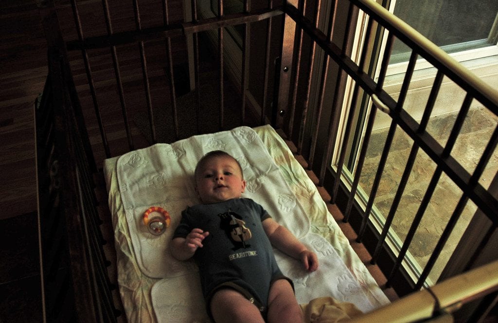 It's a cute kid on his crib waiting for mommy to play with her