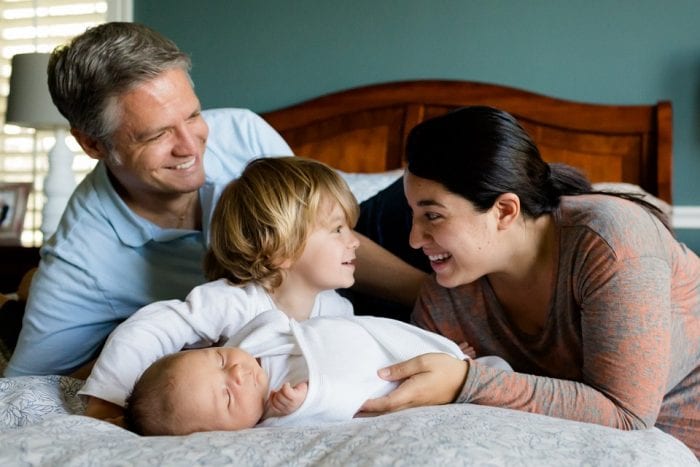 Both parents are waking a child up after sleeping for ten to twelve hours