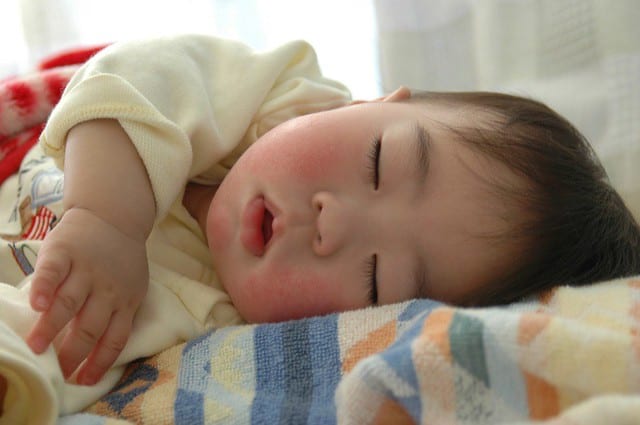 A napping baby with pink cheeks, chubby face