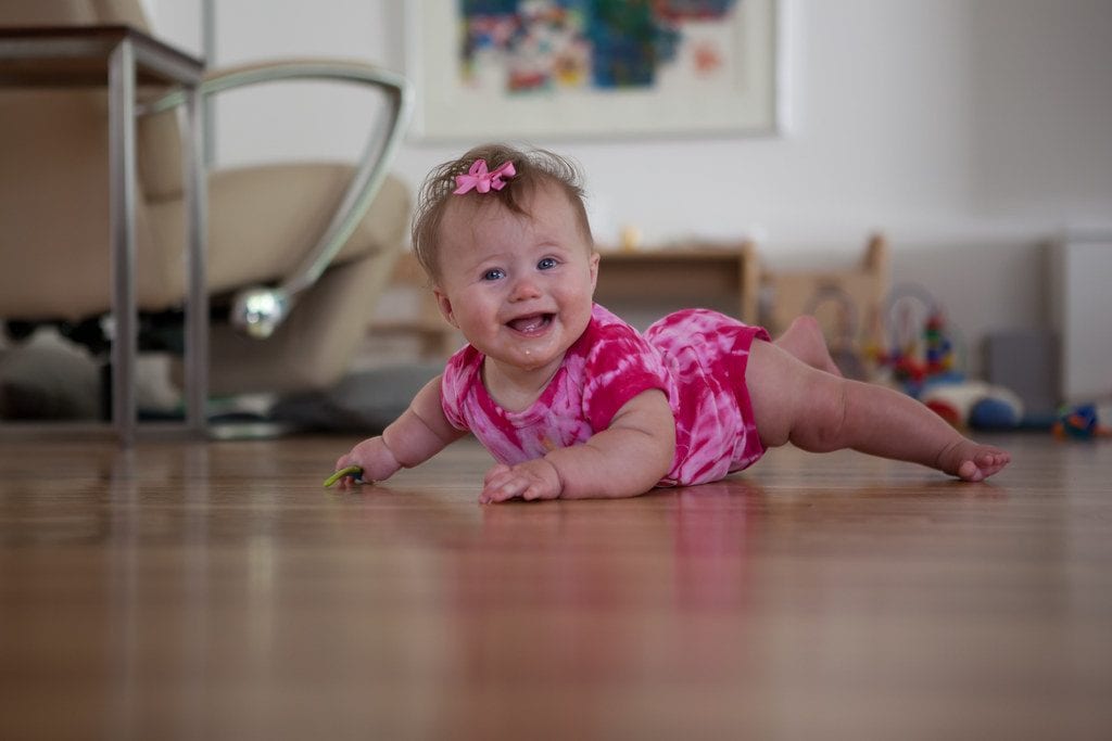 A cute baby girl trying to crawl to enhance her leg strength. You may see your little one do the rocking back and forth as a result