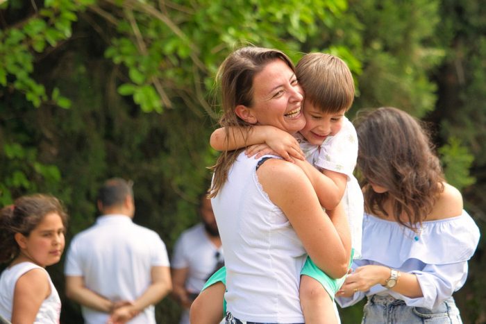 A clingy child hugs his mother tightly in the crowd. 