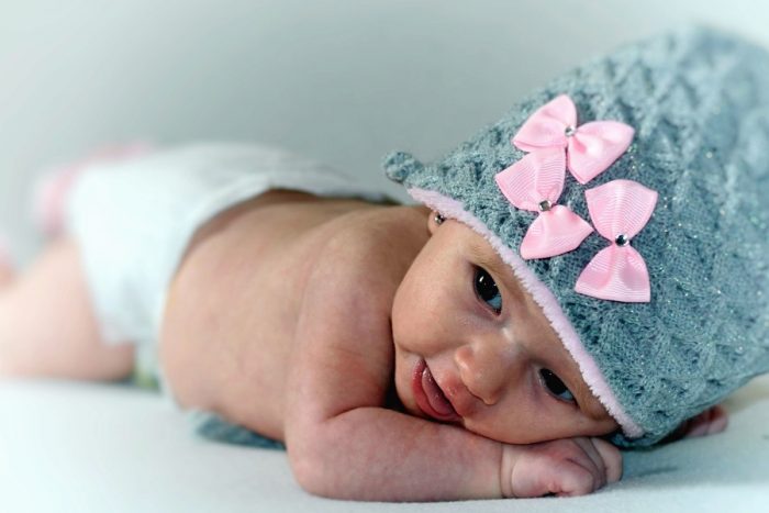 a baby in a gray bonnet with pink ribbons