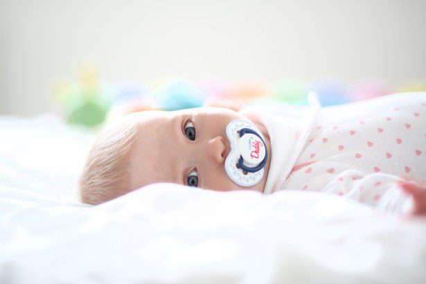 Infant peacefully lying in a best comfortable crib with a pacifier.