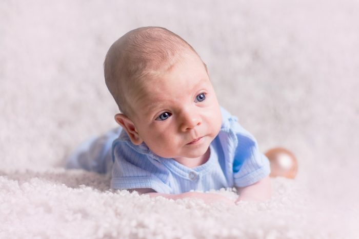 a baby doing tummy time. tummy time is encouraged, but letting a very young baby sleep on its stomach is dangerous and is known to put the baby at risk.