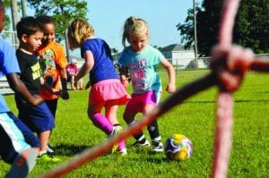 kids playing football happily on the grassy area smiling all around