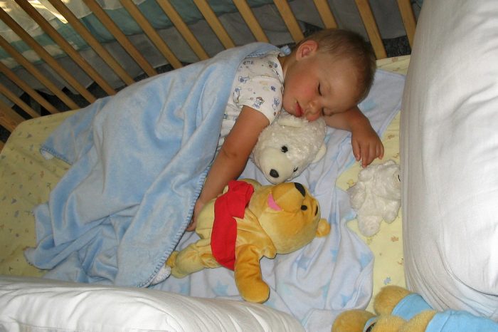 A baby sleeping in his crib with stuffed animals