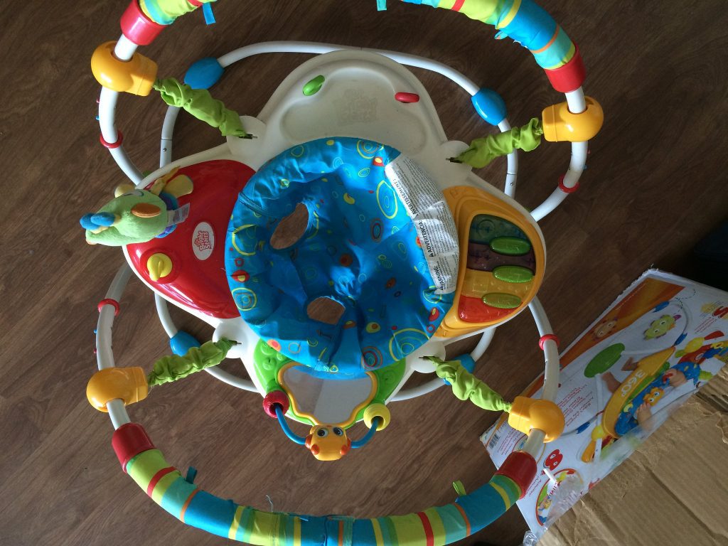 A colorful baby jumper on the floor. 