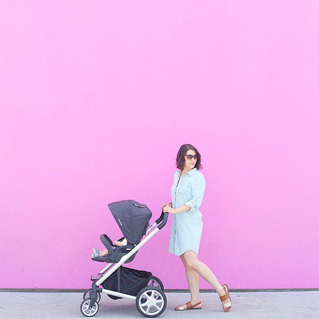 Nuna Pepp Stroller. Pink wall background with a mother pushing a stroller.