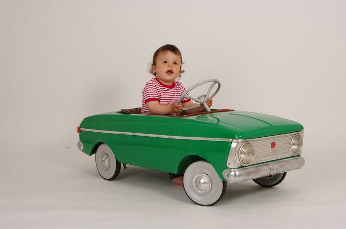 Little boy riding his favorite vintage vibe green mobile while smiling and having a great time. This is one of the top kids pedal mobiles.