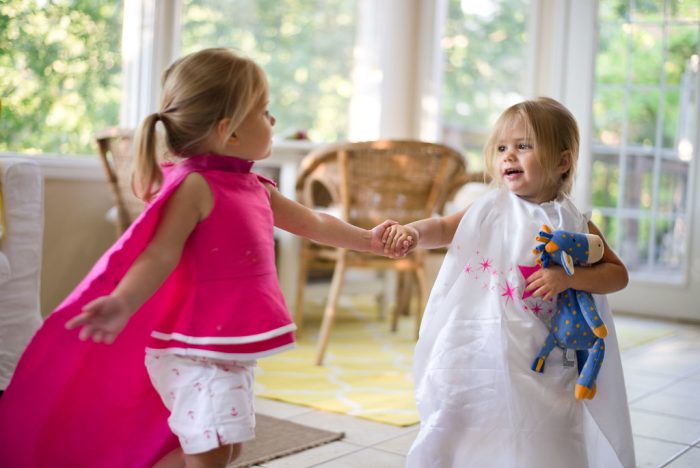 Gift for 3 year olds. A pair of adorable young girls, one draped in a delicate pink attire, while the other sports an elegant white outfit and is holding a stuffed toy. The contrast in their dresses adds to the scene's color palette - presenting a visual treat with hues symbolizing innocence and charm typical of this tender age group. Their outfits may differ, but their camaraderie and playful spirit unify them on this exciting day full of joyous laughter and endless giggles.