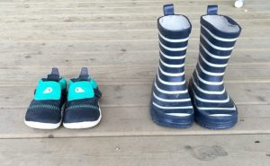 A blue-black shoes and a stripe boots on the ground. Both are good shoes for kids. 
