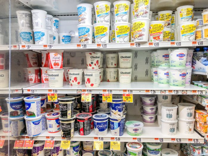 Different flavors and brands of yogurt piled neatly while being displayed in the supermarket.